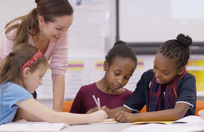 teaching assistant helping students learn french in a classroom